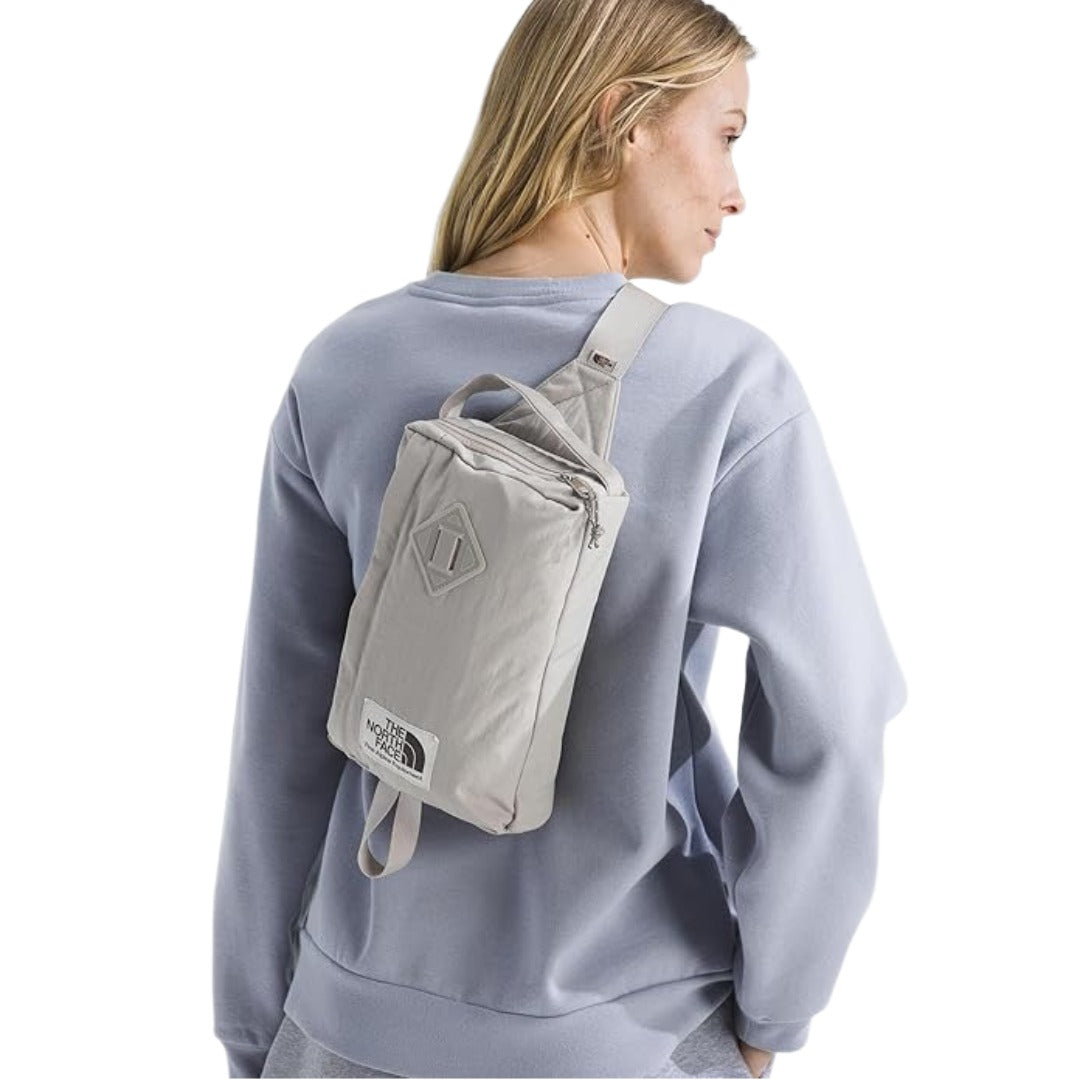The North Face Berkeley Field Bag in beige with black strap and zippered compartments, styled as a compact crossbody bag.