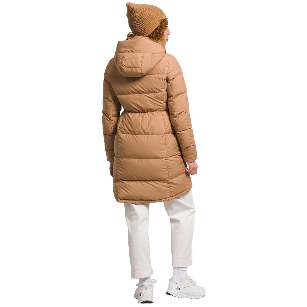 A stylish North Face Women's Metropolis Jacket in almond butter worn by a woman against a snowy backdrop.