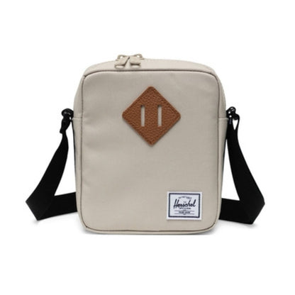 Herschel Heritage crossbody bag with a compact design, front pocket, adjustable strap, and signature diamond detail for everyday use.