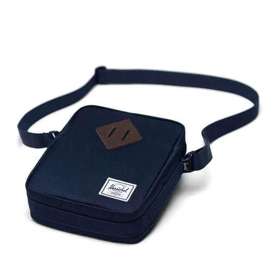 Herschel Heritage crossbody bag with a compact design, front pocket, adjustable strap, and signature diamond detail for everyday use.