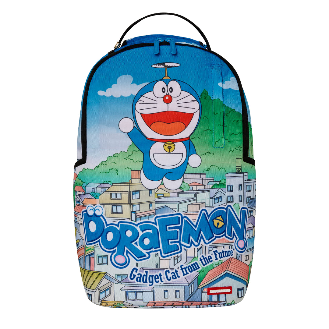Sprayground DLSXR backpack featuring Doraemon flying over a colorful cityscape with blue sky and the words “Doraemon: Gadget Cat from the Future” across the front.