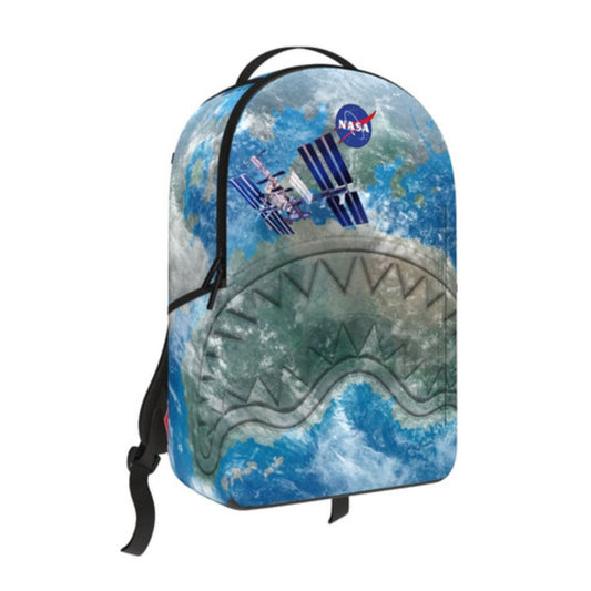 Sprayground DLXSR Backpack featuring the NASA International Space Station graphic with black and metallic detailing, official NASA patch, gold zippers, and multiple compartments.