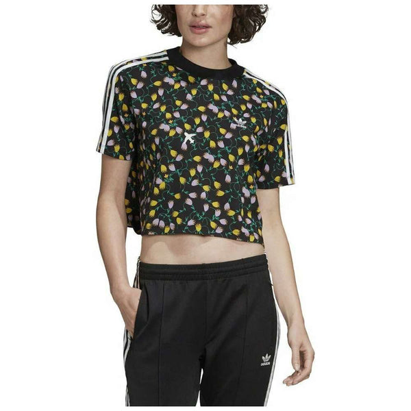 A cropped t-shirt featuring the adidas Originals logo in a vibrant all-over print, paired with high-waisted jeans. The logo creates a bold and dynamic pattern on the shirt