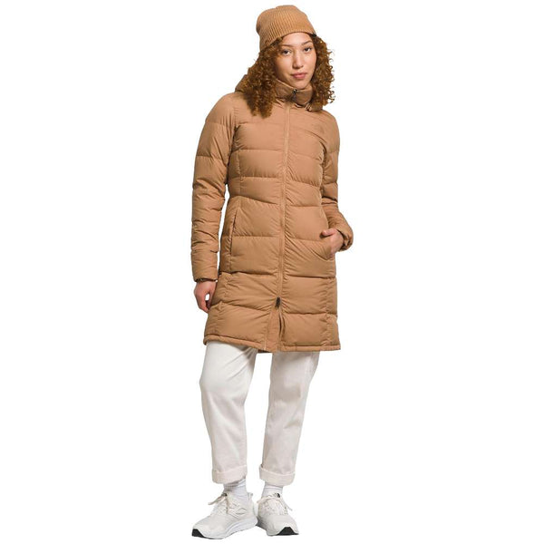 A stylish North Face Women's Metropolis Jacket in almond butter worn by a woman against a snowy backdrop.